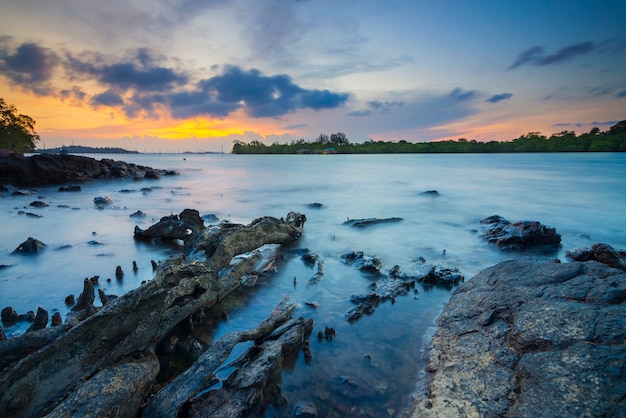 hermosa puesta de sol con rocas a lo largo de la playa