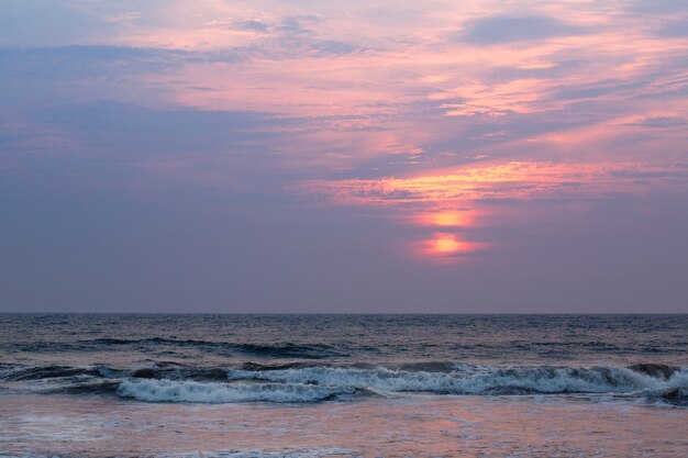 Hermosa puesta de sol rosa por el océano embravecido