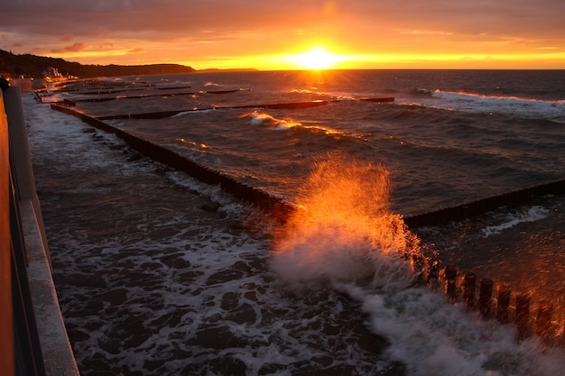 Hermosa puesta de sol sobre el mar en un clima tormentoso con reflejos rojos en el spray y la espuma del mar