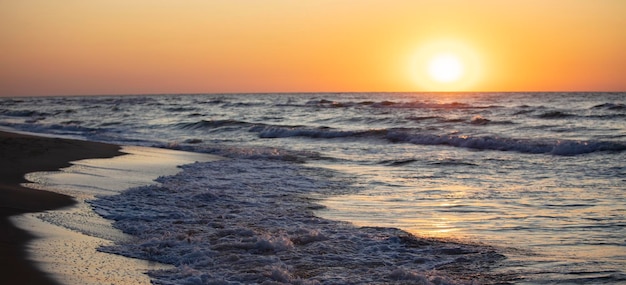 Hermosa puesta de sol sobre el mar Sol rojo y olas