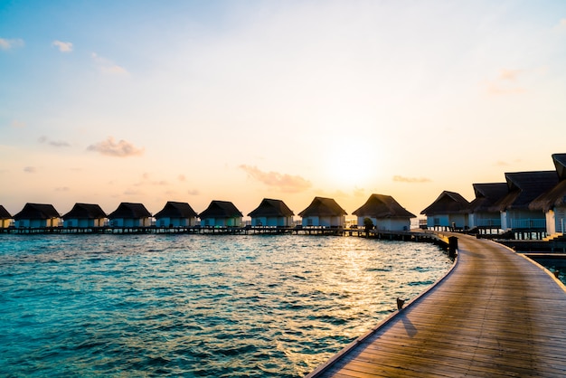 Hermosa puesta de sol tropical sobre la isla de Maldivas con bungalow de agua en hotel resort