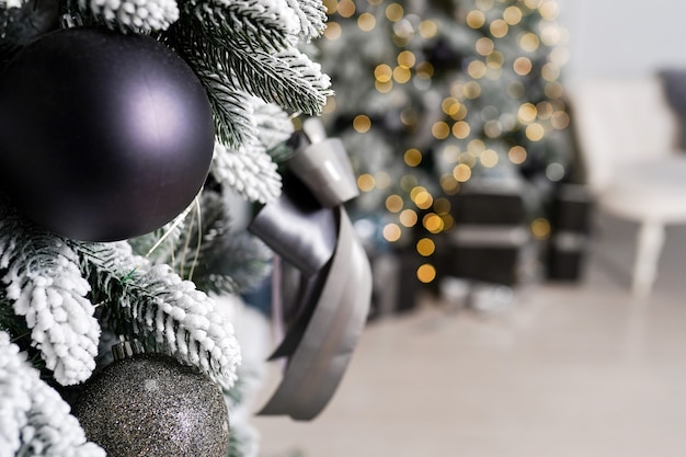 Hermosa rama de árbol de Navidad festiva está en la habitación decorada con bolas de juguetes de Navidad negros y lazo