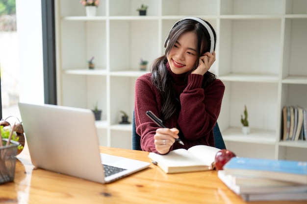 Una hermosa y relajada mujer asiática disfruta de la música en sus auriculares en una cafetería.