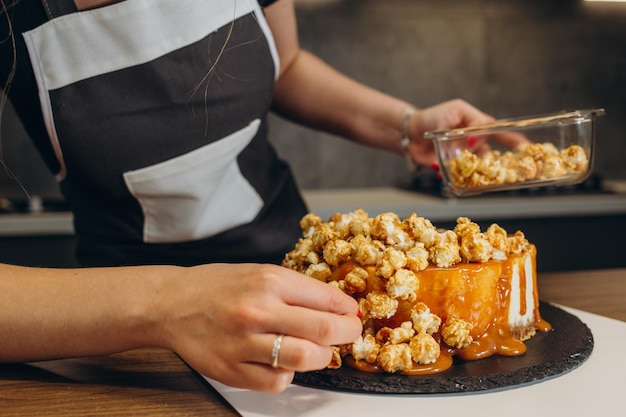 Hermosa repostera en la cocina de su casa rocía pastel de palomitas de maíz Vista de cerca