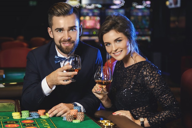 Hermosa y rica pareja jugando a la ruleta en el casino