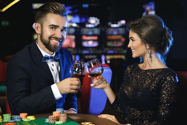 Hermosa y rica pareja jugando a la ruleta en el casino