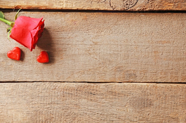 Hermosa rosa con corazones pequeños sobre fondo de madera