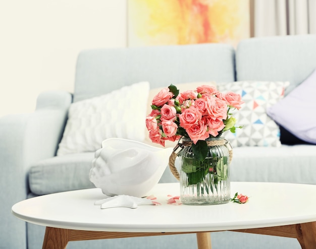 Hermosa rosa en un jarrón sobre la mesa en la habitación