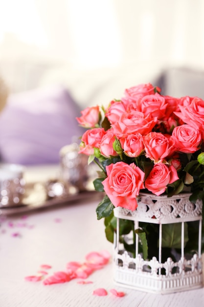 Hermosa rosa en un jarrón sobre la mesa en la habitación