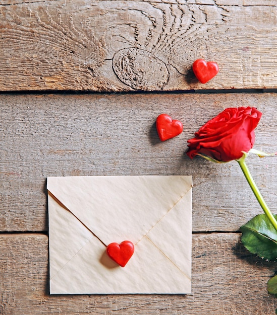 Hermosa rosa con tarjeta de regalo sobre fondo de madera