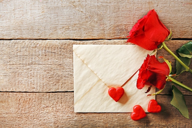 Hermosa rosa con tarjeta de regalo sobre fondo de madera