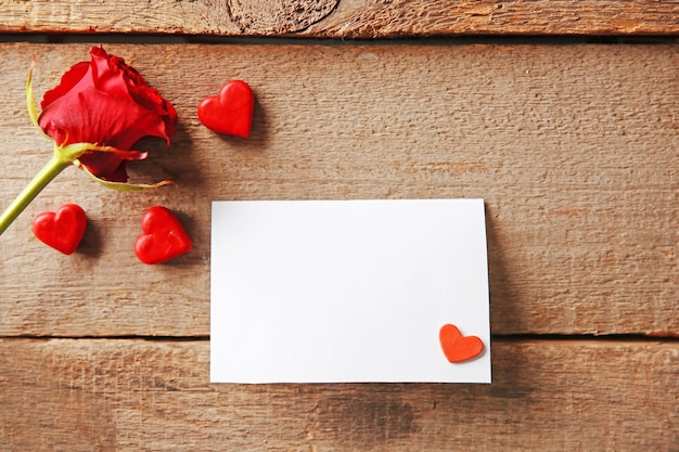 Hermosa rosa con tarjeta de regalo sobre fondo de madera