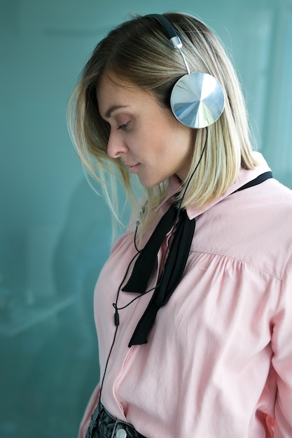 Hermosa rubia en auriculares plateados escucha música