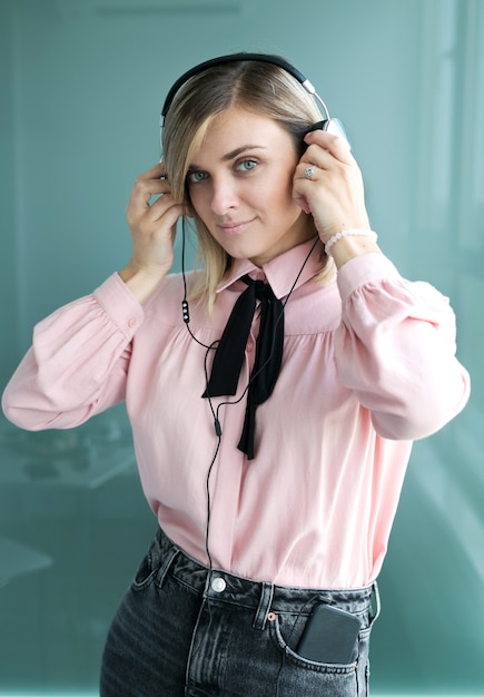 Hermosa rubia en auriculares plateados escucha música