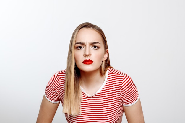 Una hermosa rubia con una camiseta blanca y roja posa en el estudio sobre un fondo blanco.