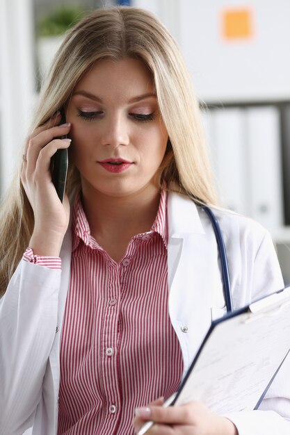 Hermosa rubia doctora hablando por teléfono