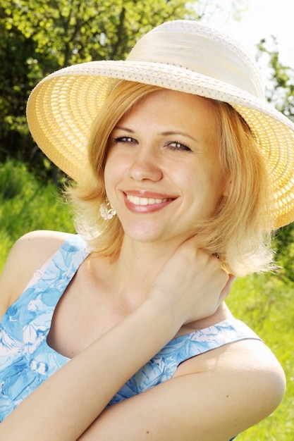 Hermosa rubia con un gran sombrero en la naturaleza