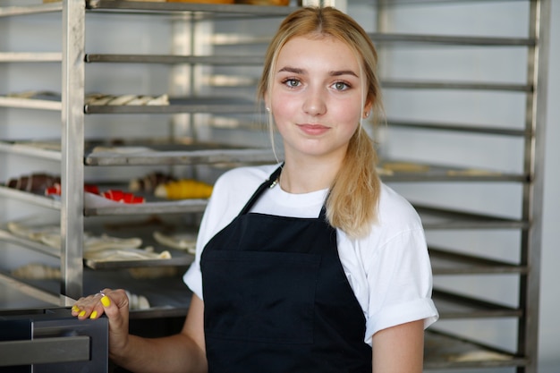 Hermosa rubia panadera en una mini panadería