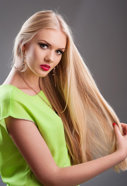 Hermosa rubia de pelo largo con un vestido verde claro.