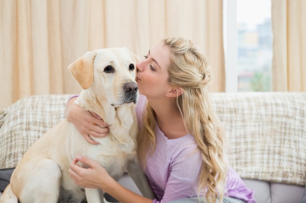 Hermosa rubia relajante en el sofá con perro mascota