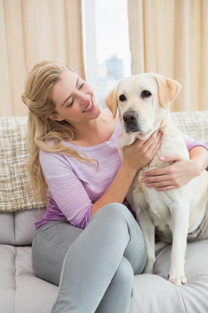 Hermosa rubia relajante en el sofá con perro mascota