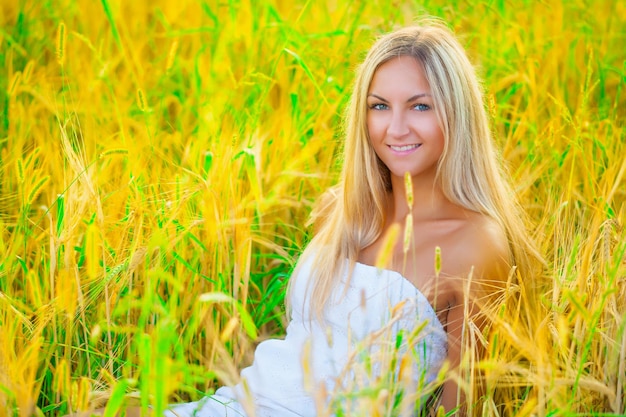 Una hermosa rubia sentada en el trigo.