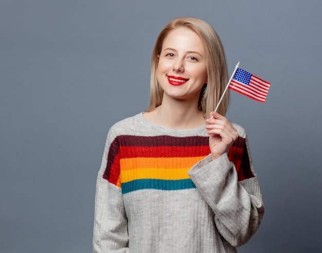 Hermosa rubia en suéter con la bandera de Estados Unidos en gris