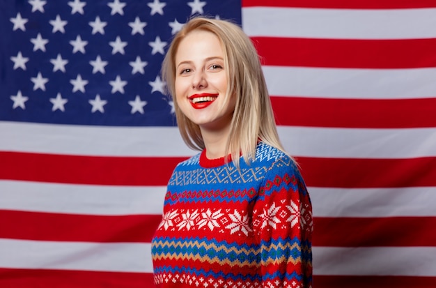 Hermosa rubia en suéter de Navidad en la bandera de Estados Unidos