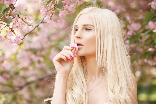 Hermosa rubia con el telón de fondo de un floreciente jardín de sakura