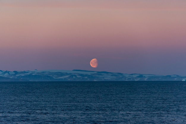 Hermosa salida de la luna en Groenlandia. Iceberg en el mar.