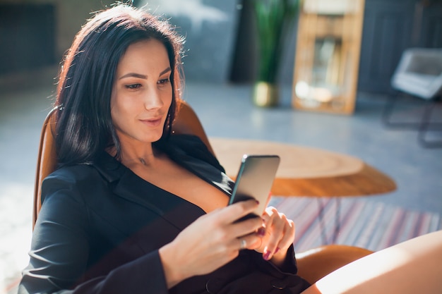 Hermosa sexy blogger con smartphone en casa.