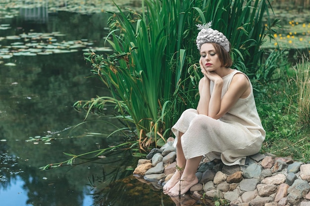 Foto una hermosa sirena joven con una corona de conchas está sentada en el fondo del agua mermaid cosplay