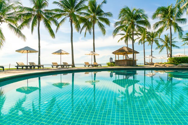 Hermosa sombrilla y silla alrededor de la piscina en el hotel y resort