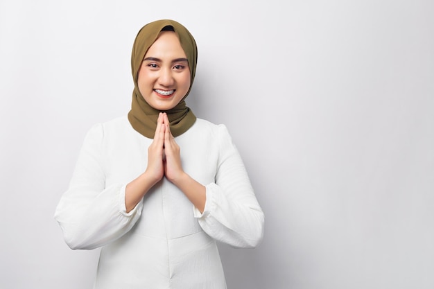 Hermosa sonriente amable joven árabe asiática musulmana con hiyab de pie gesticulando Eid Mubarak saludo aislado sobre fondo blanco Concepto de estilo de vida religioso de la gente