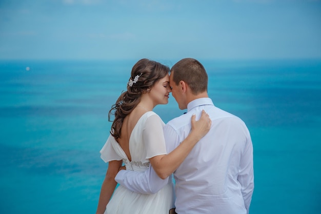 Hermosa y sonriente novia y novio caminando por la playa besándose y divirtiéndose ceremonia de boda cerca de las rocas y el mar Ceremonia de boda en la costa de Chipre