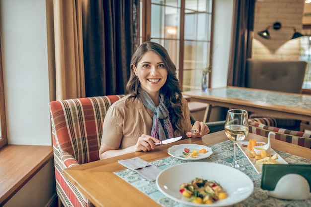 Hermosa sonrisa. Mujer joven sentada a la mesa en un restaurante y sonriendo amablemente