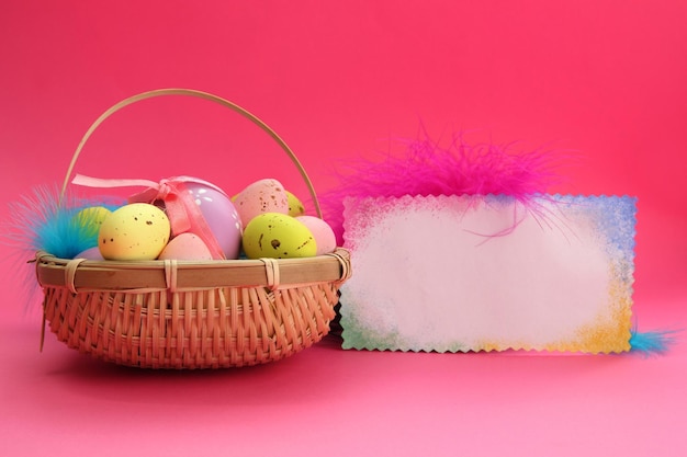 Hermosa tarjeta de pascua en blanco y huevos en canasta sobre fondo rosa