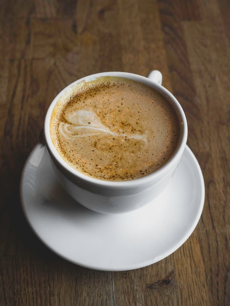 Una hermosa taza de capuchino con arte latte en el fondo de madera Composición mínima Copie el espacio para su texto