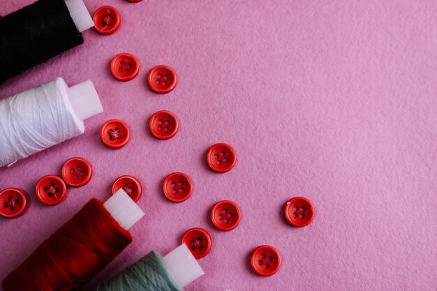 Hermosa textura con muchos botones rojos redondos para coser y madejas de carretes