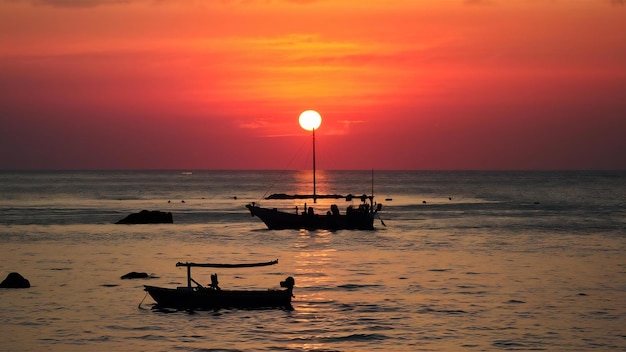 Una hermosa toma de la puesta de sol en la orilla del mar con un barco en el medio