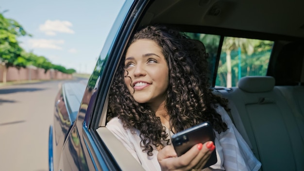 Hermosa turista latina viajando en taxi y reescrita con tus amigos en tu smartphone