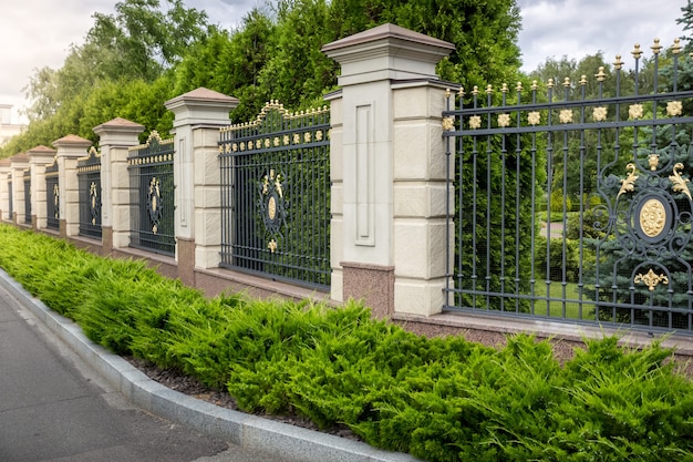 Hermosa valla forjada pintada con oro en la entrada a la villa de lujo