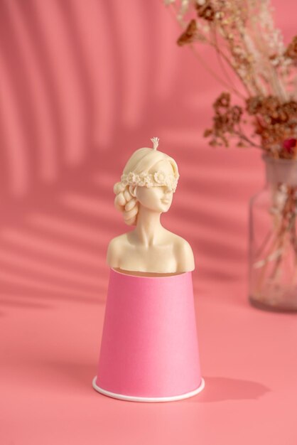 Hermosa vela hecha a mano en forma de cuerpo femenino sobre un soporte y fondo rosa