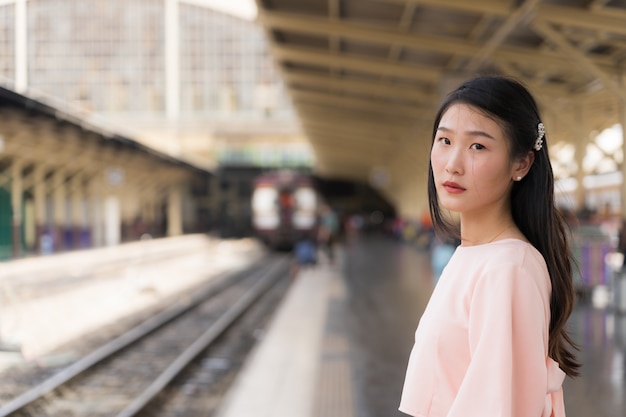 Hermosa viajera esperando el tren en la estación