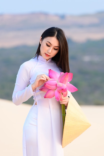 Hermosa vietnamita con loto rosa en el desierto de dunas de arena blanca, Muine, Vietnam