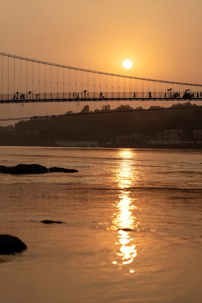 Hermosa vista del agua del río Ganges y el puente Ram Jhula al atardecer. Rishikesh, India