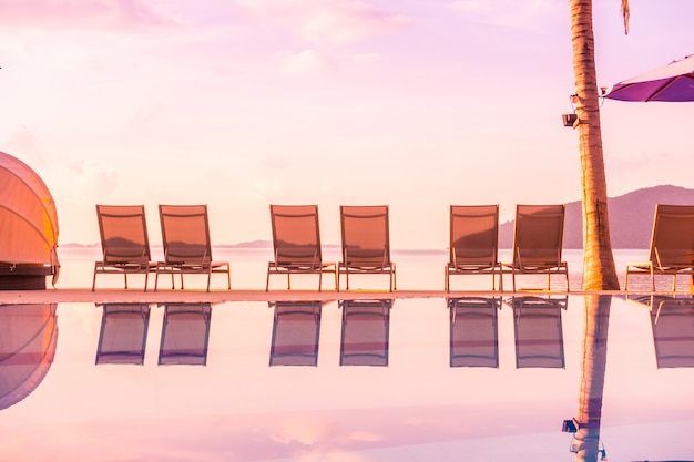 Hermosa vista al aire libre con sombrilla y silla alrededor de la piscina en hotel de lujo y resort