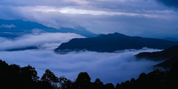 Hermosa vista del atardecer sobre la cordillera cubierta de clounds. Concepto de actividad de trekking y senderismo. Foto de archivo del paisaje.