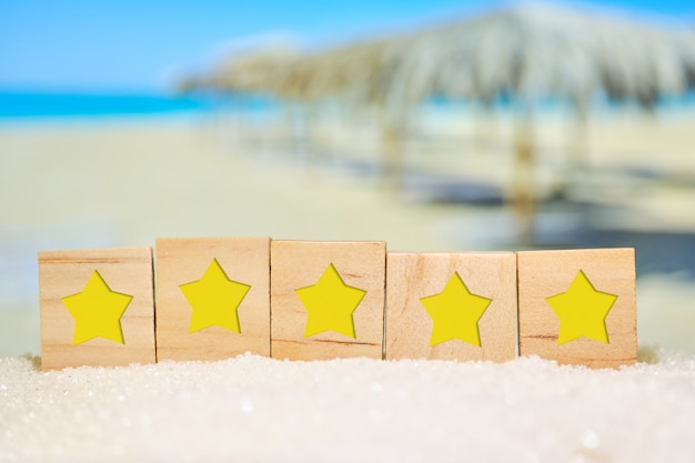 Hermosa vista borrosa de la playa con cubos de madera con estrellas. Concepto de rating, evaluación de las mejores playas del mundo.