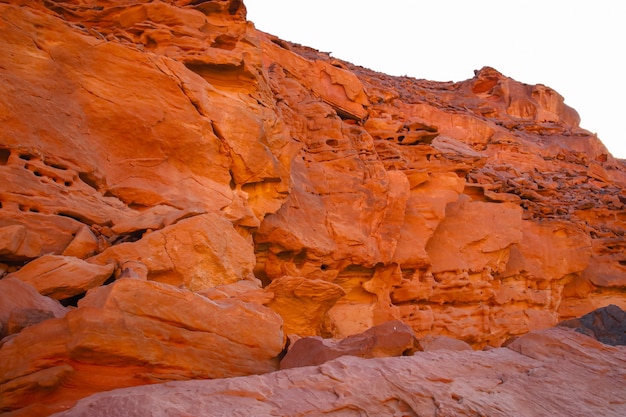 Una hermosa vista de un cañón del desierto de montaña de color rojo contra el fondo de un cielo azul y un sol abrasador